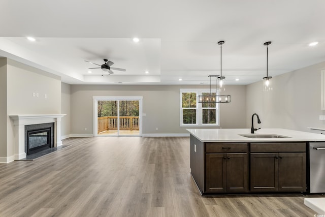 kitchen featuring a premium fireplace, a tray ceiling, recessed lighting, a sink, and stainless steel dishwasher