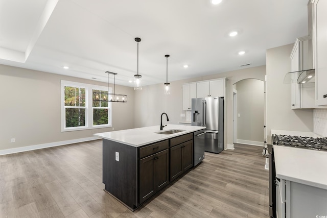 kitchen with a sink, stainless steel appliances, arched walkways, and light countertops