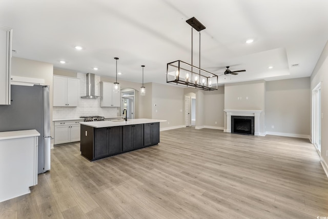 kitchen with arched walkways, freestanding refrigerator, a high end fireplace, light countertops, and wall chimney exhaust hood