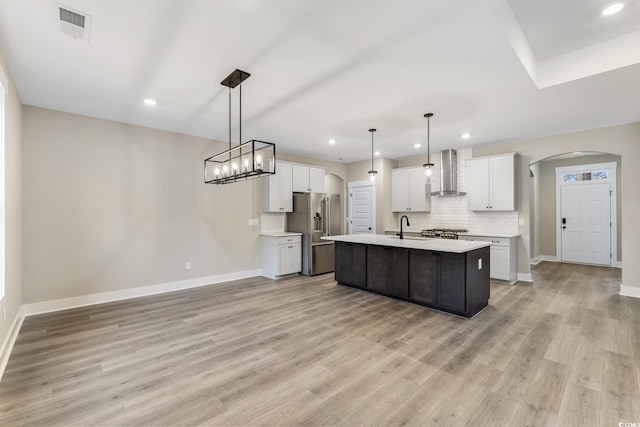 kitchen with visible vents, high quality fridge, arched walkways, wall chimney exhaust hood, and a sink