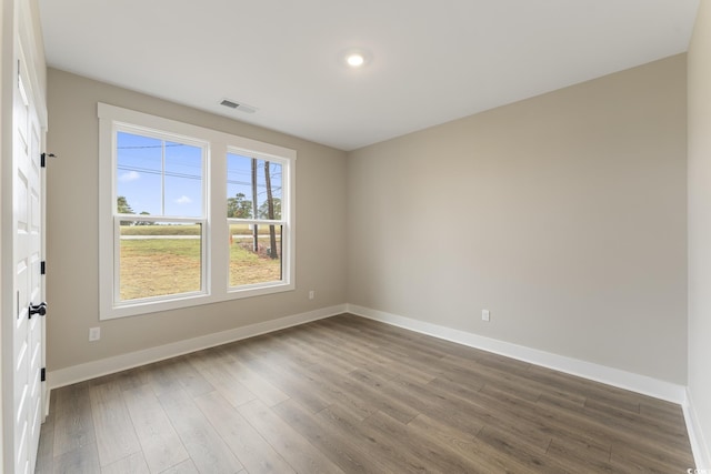 spare room featuring dark wood-style floors, visible vents, and baseboards