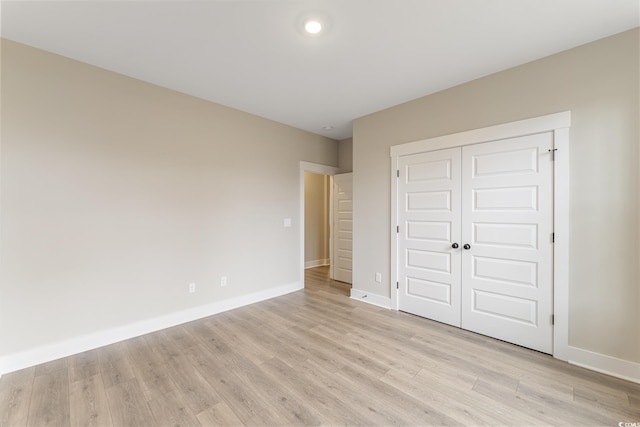 unfurnished bedroom with a closet, light wood-type flooring, and baseboards