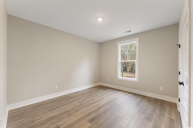 empty room with visible vents, baseboards, and wood finished floors