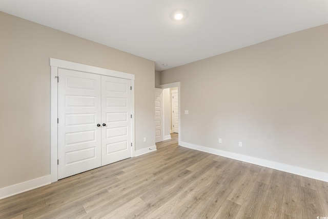 unfurnished bedroom with a closet, baseboards, and light wood finished floors