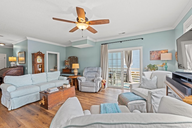 living room with visible vents, ornamental molding, ceiling fan, and wood finished floors