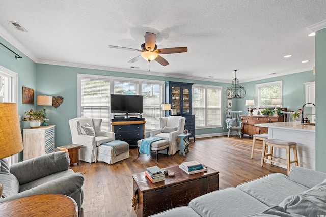 living room featuring visible vents, crown molding, and wood finished floors