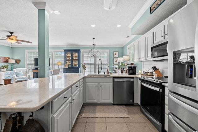 kitchen featuring crown molding, light tile patterned floors, a wealth of natural light, stainless steel appliances, and a sink