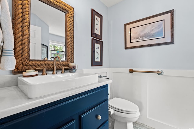 bathroom with a wainscoted wall, toilet, and vanity