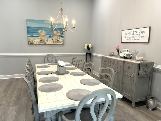 dining area featuring a notable chandelier, baseboards, and wood finished floors