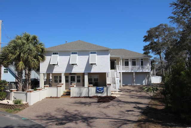 view of front of house featuring a shingled roof, a fenced front yard, stairway, covered porch, and decorative driveway