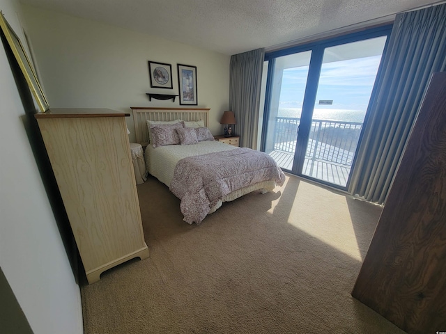 bedroom with a wall of windows, access to exterior, carpet floors, and a textured ceiling