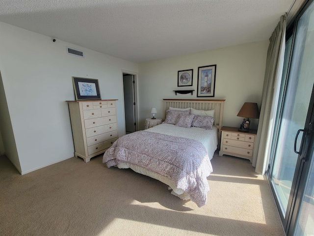 bedroom with visible vents, light carpet, and a textured ceiling