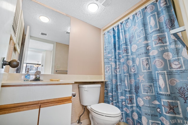 bathroom featuring visible vents, toilet, vanity, and a textured ceiling