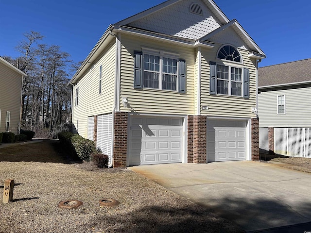 exterior space with brick siding, an attached garage, and driveway