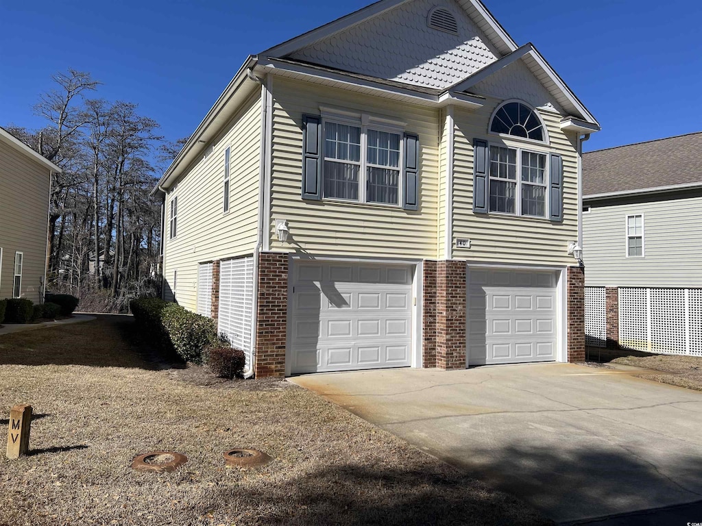 view of front of property featuring a garage, brick siding, and driveway