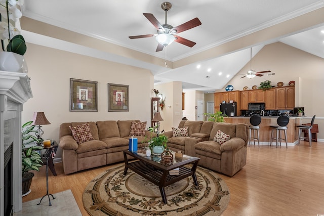 living area with light wood-style floors, crown molding, a ceiling fan, and a tile fireplace