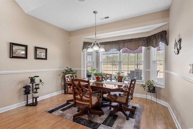 dining area featuring visible vents, baseboards, and wood finished floors
