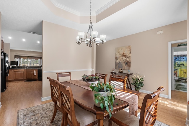 dining area featuring baseboards, light wood finished floors, ornamental molding, a raised ceiling, and a notable chandelier