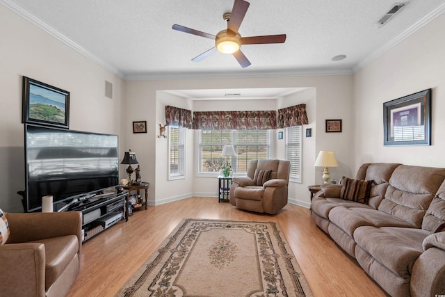 living area with visible vents, ornamental molding, and wood finished floors