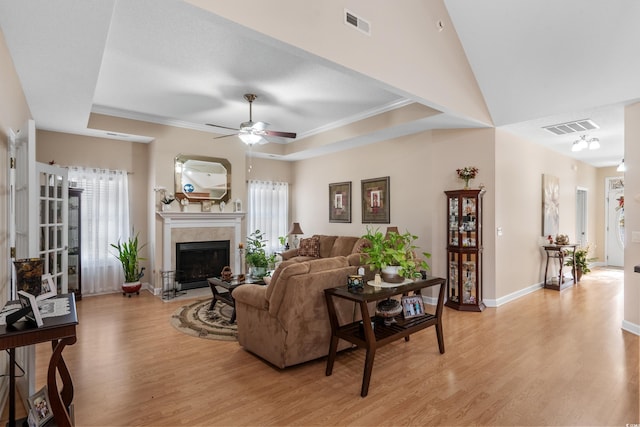 living room with light wood finished floors, visible vents, plenty of natural light, and a tray ceiling