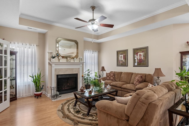 living area with visible vents, a fireplace with flush hearth, ornamental molding, a ceiling fan, and light wood finished floors
