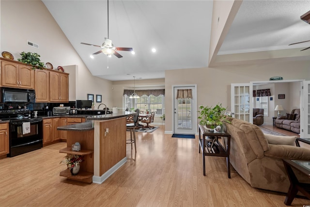 kitchen featuring light wood-style flooring, black appliances, a kitchen bar, ceiling fan with notable chandelier, and open floor plan