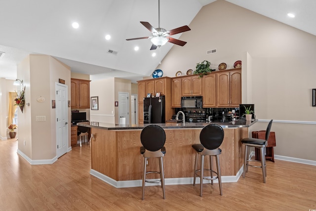 kitchen with visible vents, a breakfast bar area, a peninsula, and black appliances