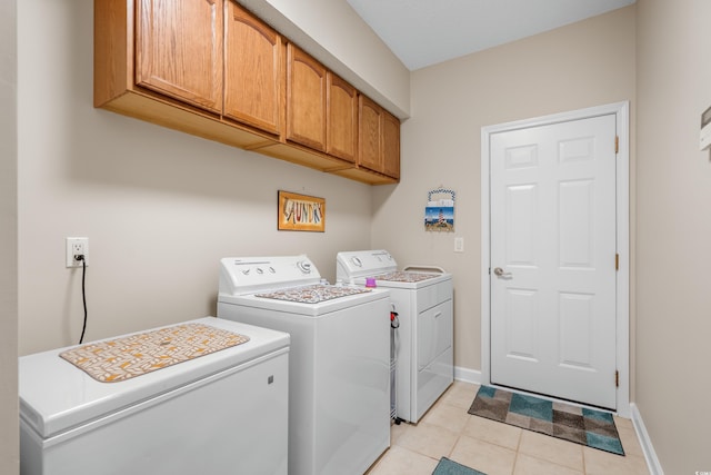washroom featuring cabinet space, washer and dryer, baseboards, and light tile patterned flooring