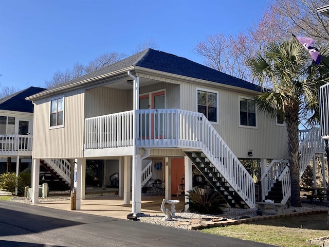 exterior space with stairs, a carport, a porch, and roof with shingles