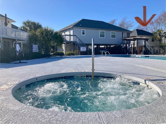 view of pool with fence and a hot tub