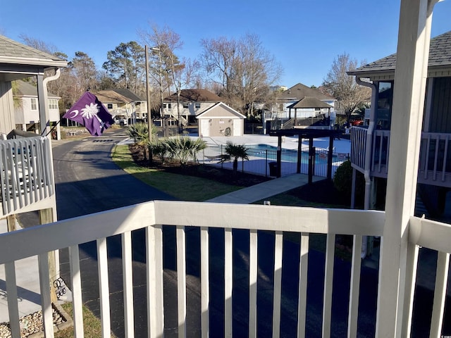 view of yard with a residential view, fence, a balcony, and a community pool