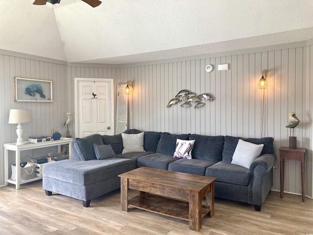 living area with vaulted ceiling, light wood-style flooring, a ceiling fan, and a textured ceiling