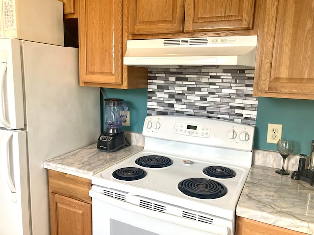 kitchen featuring white appliances, light countertops, tasteful backsplash, and under cabinet range hood