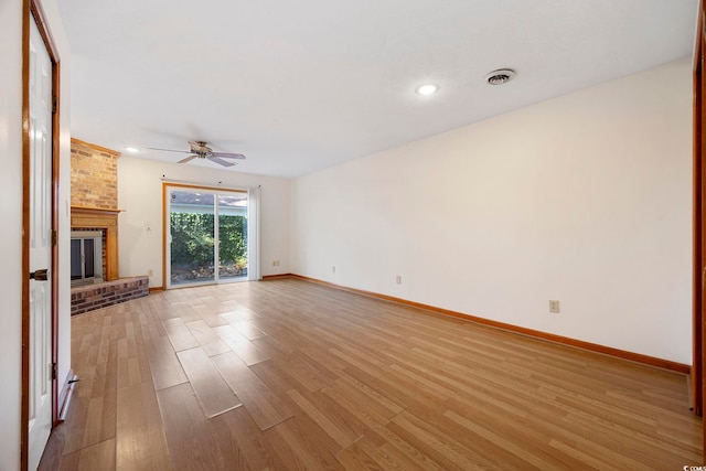 unfurnished living room with visible vents, ceiling fan, baseboards, a fireplace, and light wood-style floors