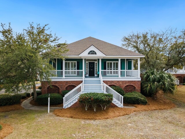 beach home featuring stairs, a porch, and a shingled roof