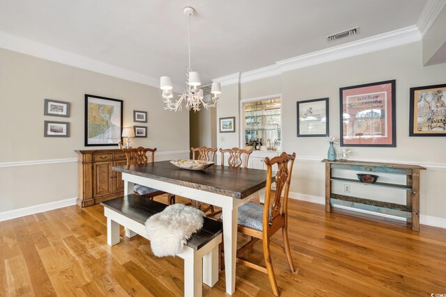 dining room featuring visible vents, light wood-style flooring, and crown molding