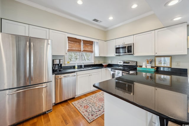 kitchen with dark countertops, visible vents, ornamental molding, white cabinets, and stainless steel appliances