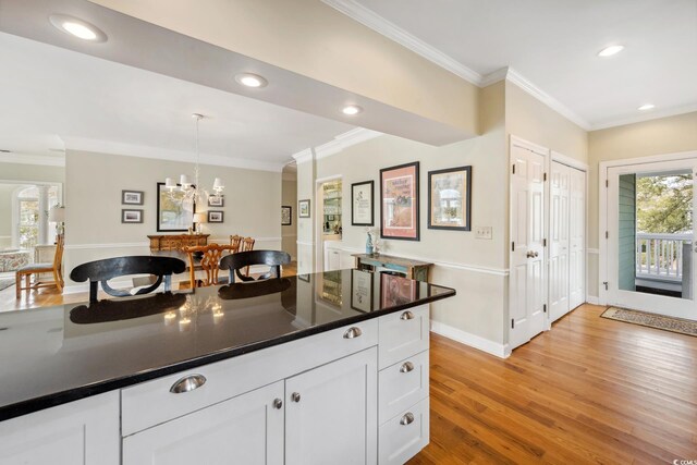 kitchen with light wood finished floors, white cabinetry, and crown molding