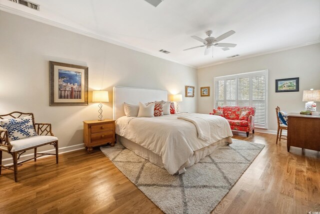 bedroom with visible vents, crown molding, baseboards, and wood finished floors