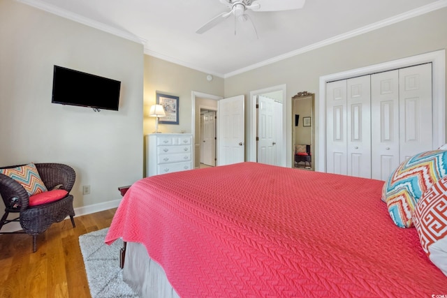 bedroom with crown molding, baseboards, wood finished floors, a closet, and a ceiling fan