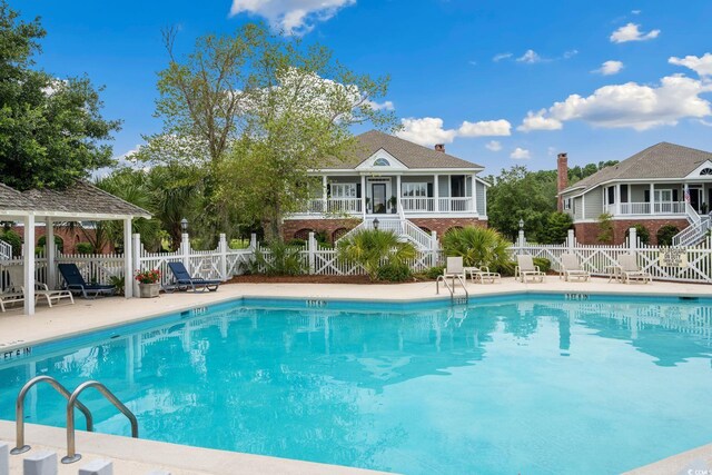 community pool with a patio area, a gazebo, stairs, and fence