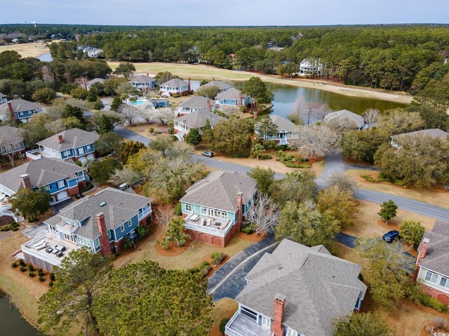 drone / aerial view with a residential view, a wooded view, and a water view