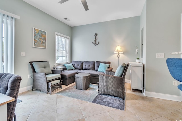 living room with light tile patterned floors, visible vents, baseboards, and a ceiling fan