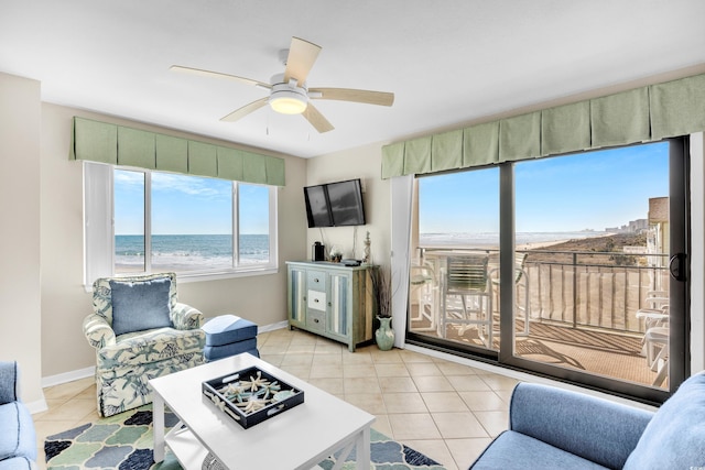 living area featuring ceiling fan, baseboards, and light tile patterned flooring