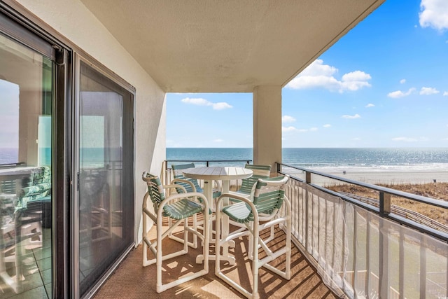 balcony with a water view and a view of the beach