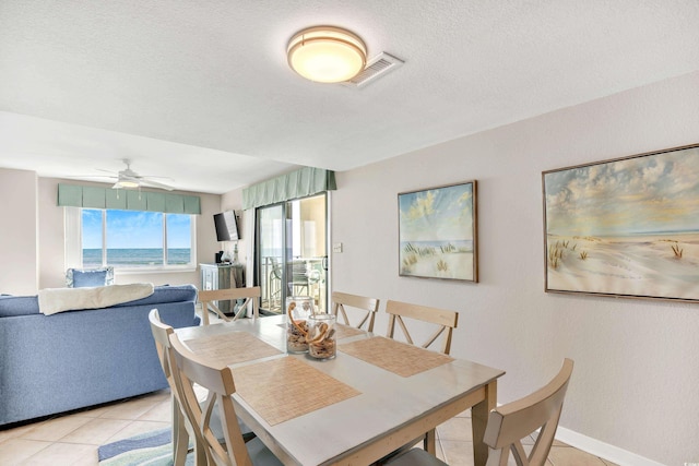 dining area with visible vents, ceiling fan, baseboards, light tile patterned floors, and a textured ceiling