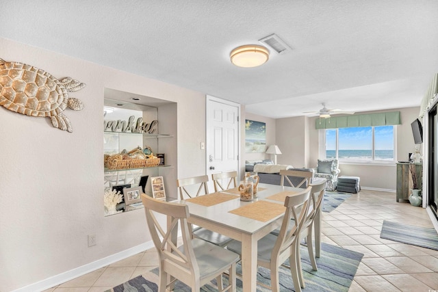 dining area featuring visible vents, a textured ceiling, light tile patterned flooring, baseboards, and ceiling fan