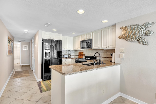 kitchen featuring light stone counters, light tile patterned floors, a sink, decorative backsplash, and black appliances