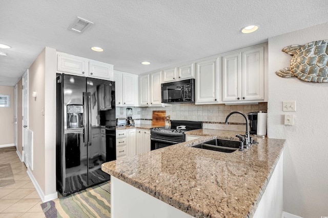 kitchen with visible vents, a peninsula, a sink, black appliances, and backsplash