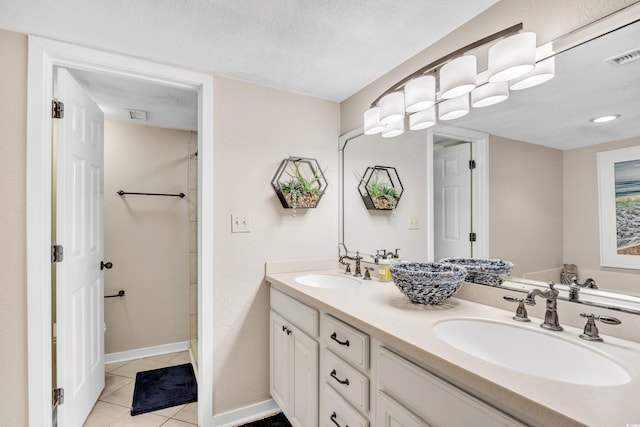 bathroom with visible vents, a sink, a textured ceiling, tile patterned flooring, and double vanity